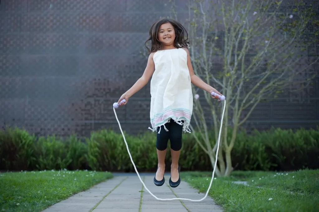 The image shows a girl jumping with a skipping rope in a white dress Best Skipping Rope